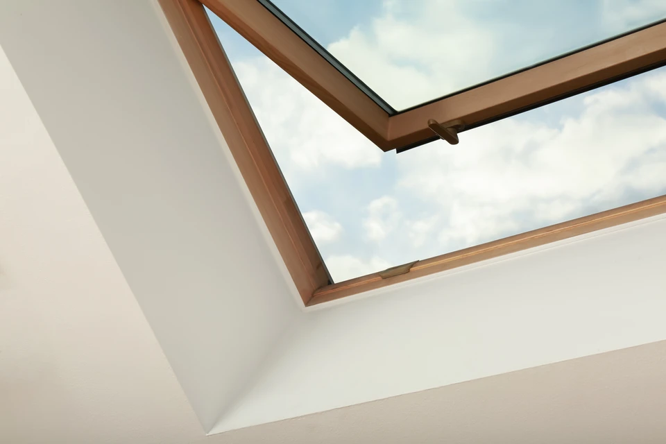 Fenêtre ouverte sur le toit de la lucarne sur plafond incliné dans la chambre mansardée, vue en basse angle