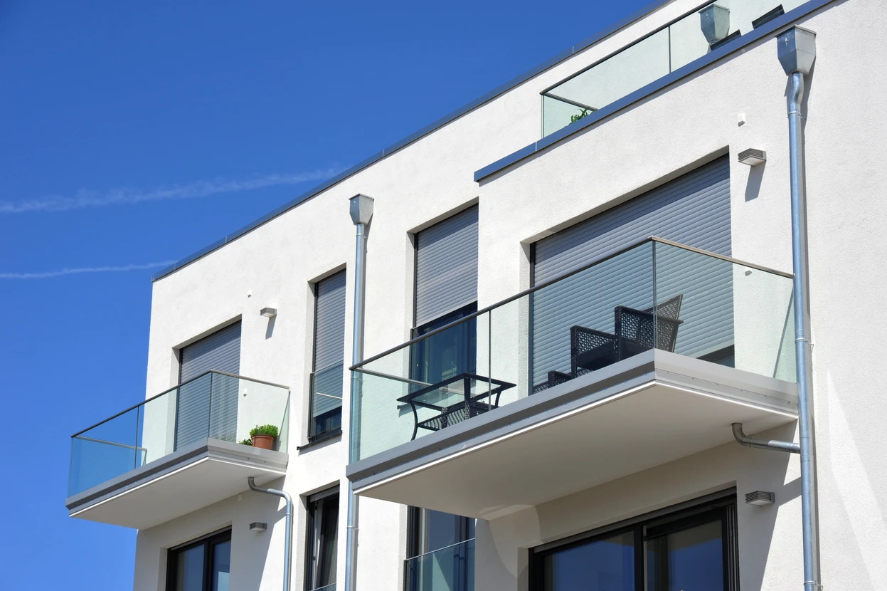 Façade d'immeuble résidentiel moderne avec balcons en verre et garde-corps transparents
