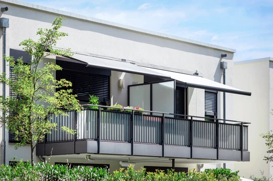 Balcon moderne d'appartement avec jardini&egrave;res suspendues noires contenant plantes vertes et fleurs color&eacute;es
