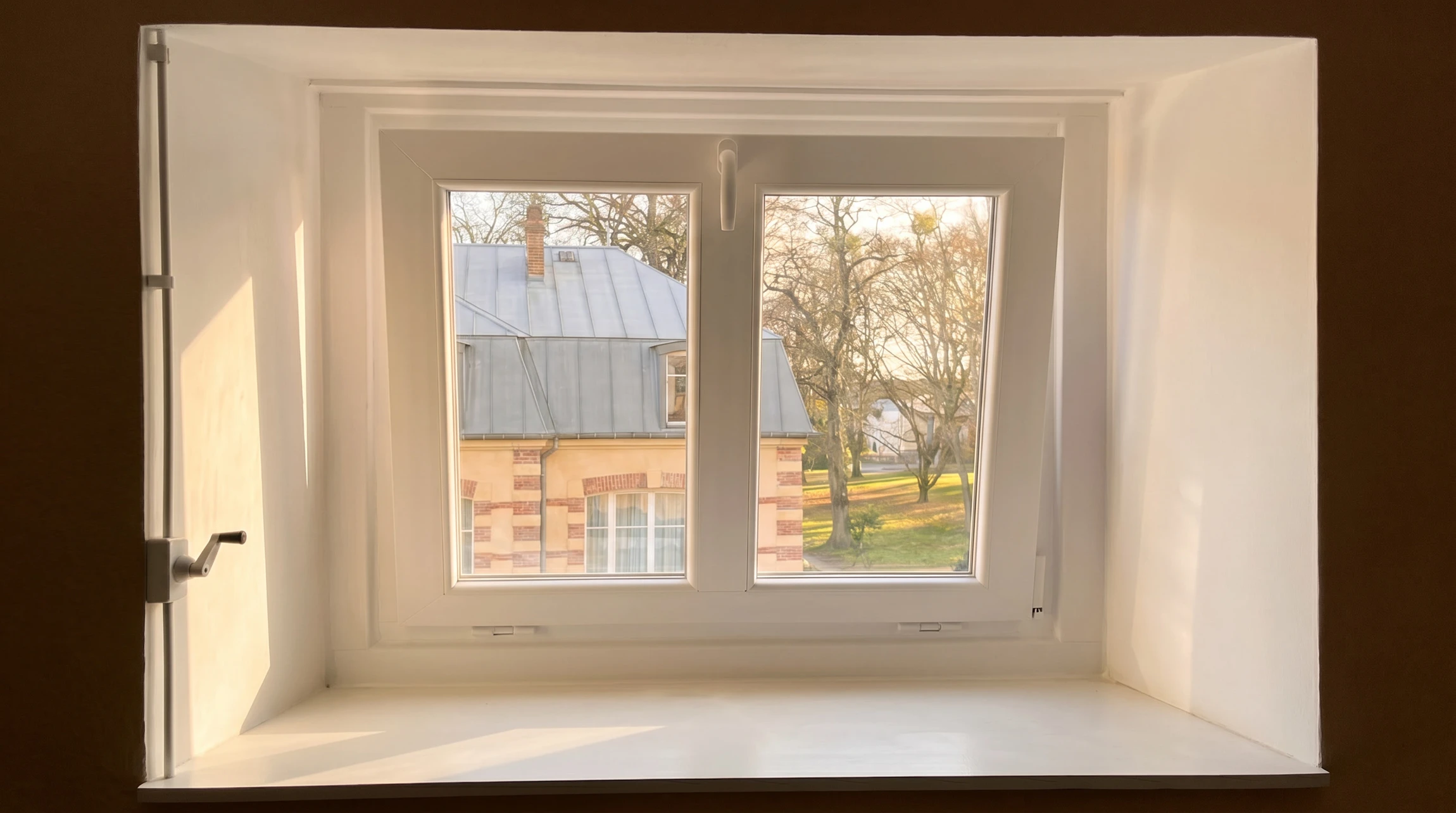 Int&eacute;rieur moderne avec escalier descendant vers niveau inf&eacute;rieur, garde-corps en verre transparent, cuisine ouverte contemporaine au fond avec &icirc;lot central sombre