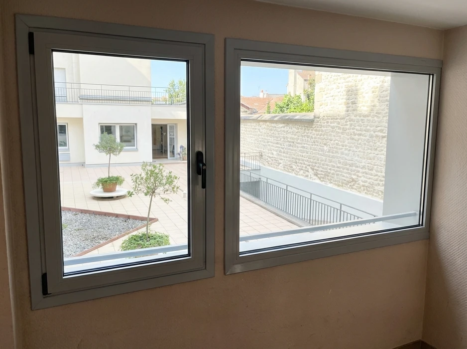 Un ouvrier installe une porte-fenêtre coulissante à châssis anthracite dans une maison en rénovation