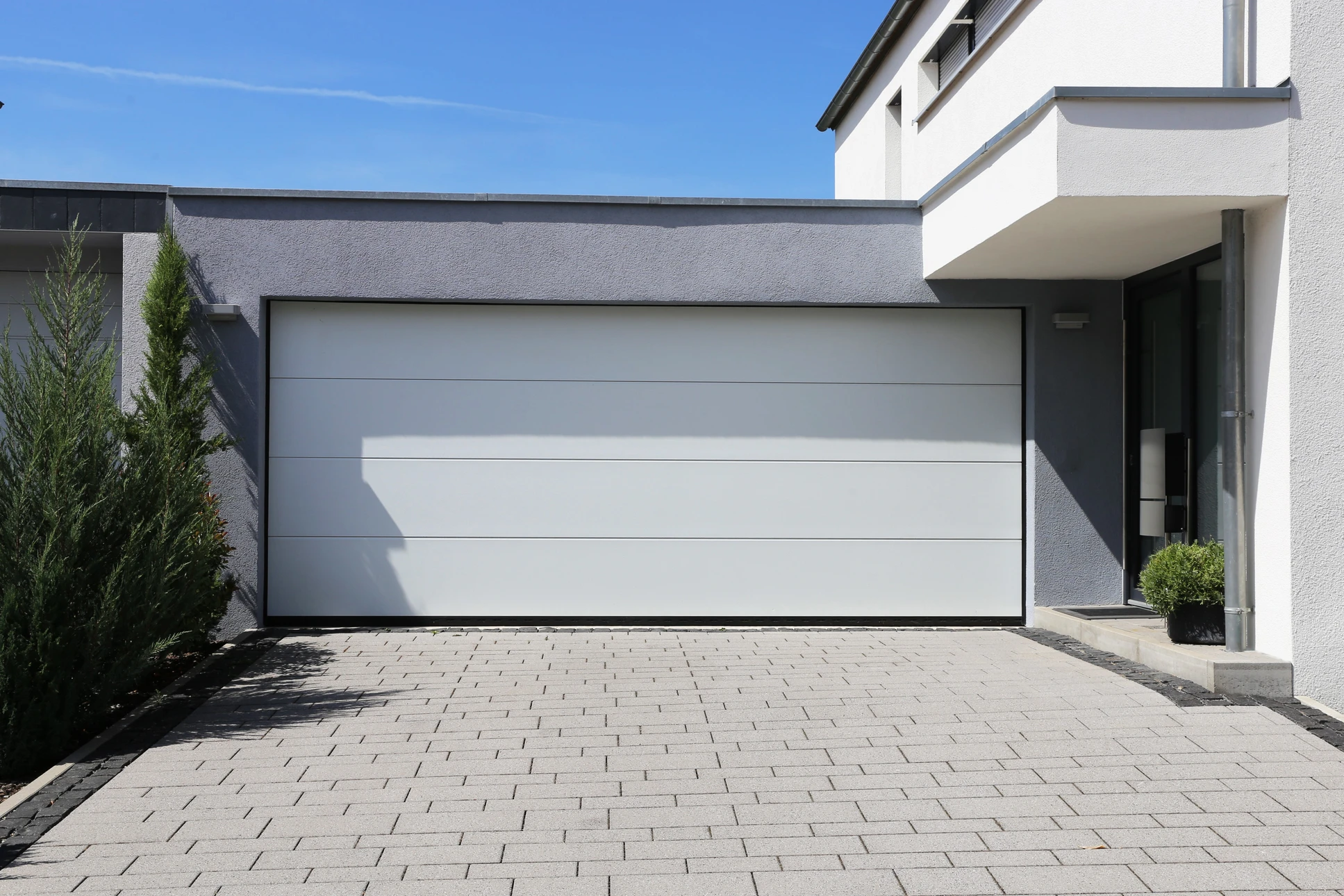 Extérieur résidentiel moderne avec porte de garage sectionnelle anthracite à quatre panneaux horizontaux lisses