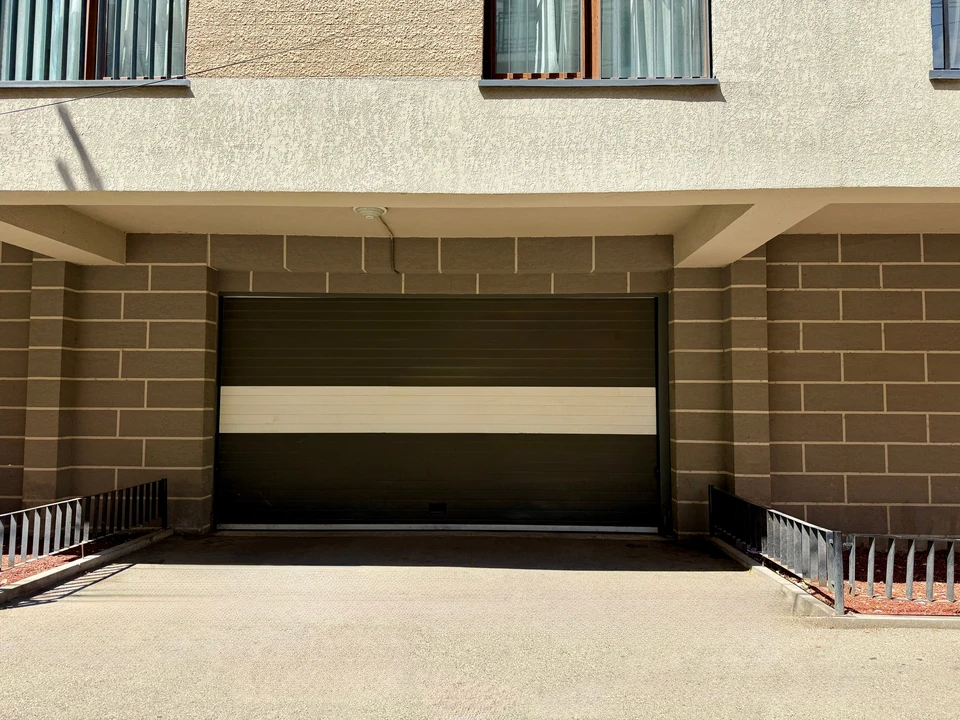 Garage résidentiel ouvert avec porte sectionnelle relevée, sol en béton lissé, éclairage encastré au plafond