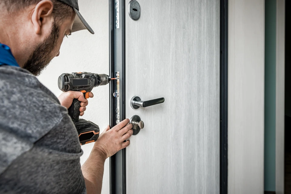 Professionnelle immobilière accueillant un couple de clients devant l'entrée d'une maison moderne